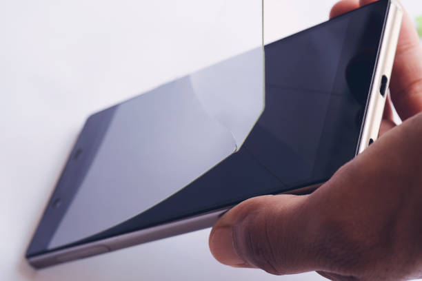 Hand removing damaged and stained protective smartphone screen film